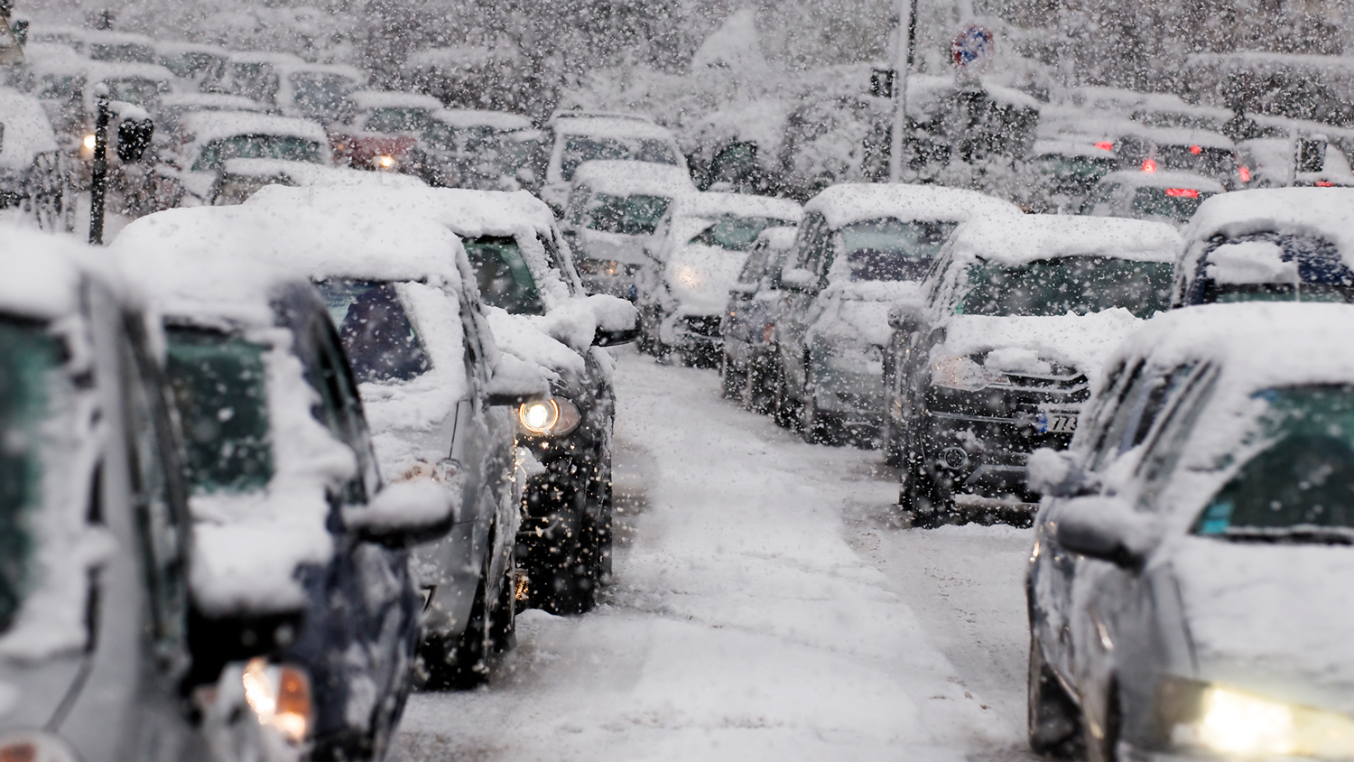 طوابير من السيارات المغطاة بالثلوج تنتظر على الطرق المغطاة بالثلوج.